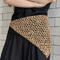 Pañuelo triangular beige con motivo de rejilla calada y lentejuelas, llevado sobre una falda negra