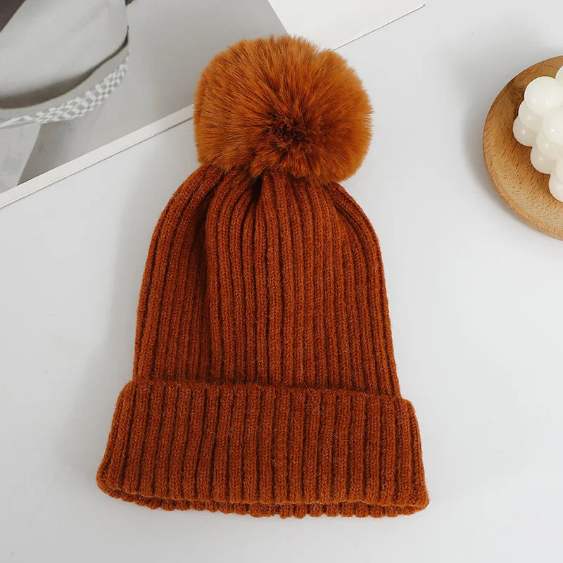 Gorro color óxido de canalé vertical con vuelta ancha y pompón suave del mismo color, colocado en plano