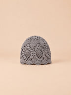 Gorro de verano gris de encaje floral con flores caladas y borde ondulado, fotografiado de frente