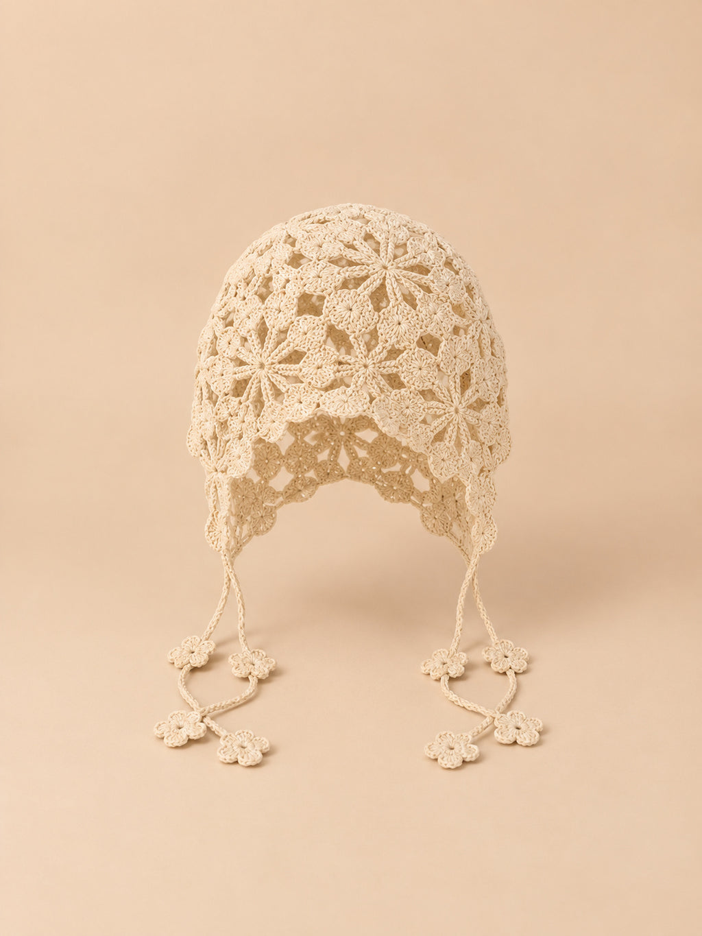 Gorro beige de rejilla calada para anudar, con cintas que permiten ajustar la sujeción, vista frontal