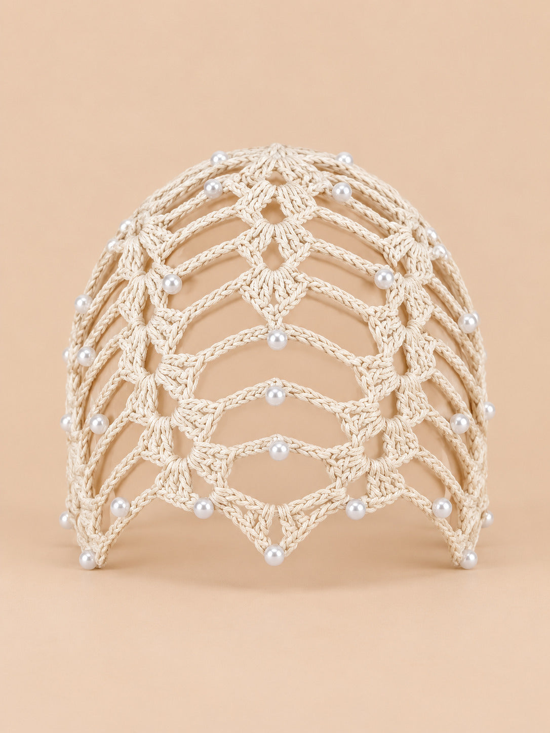 Bonnet bandana femme beige au crochet ajouré perlé, vue de face sur fond pêche sable