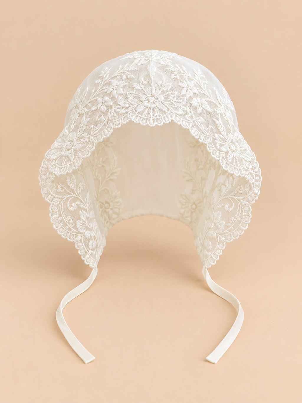 Béguin bébé fille en dentelle brodée, modèle 01, vue de face sur fond pêche sable
