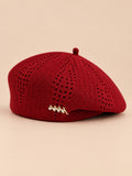 Béret ajouré style japonais rouge, vue de face sur fond pêche sable