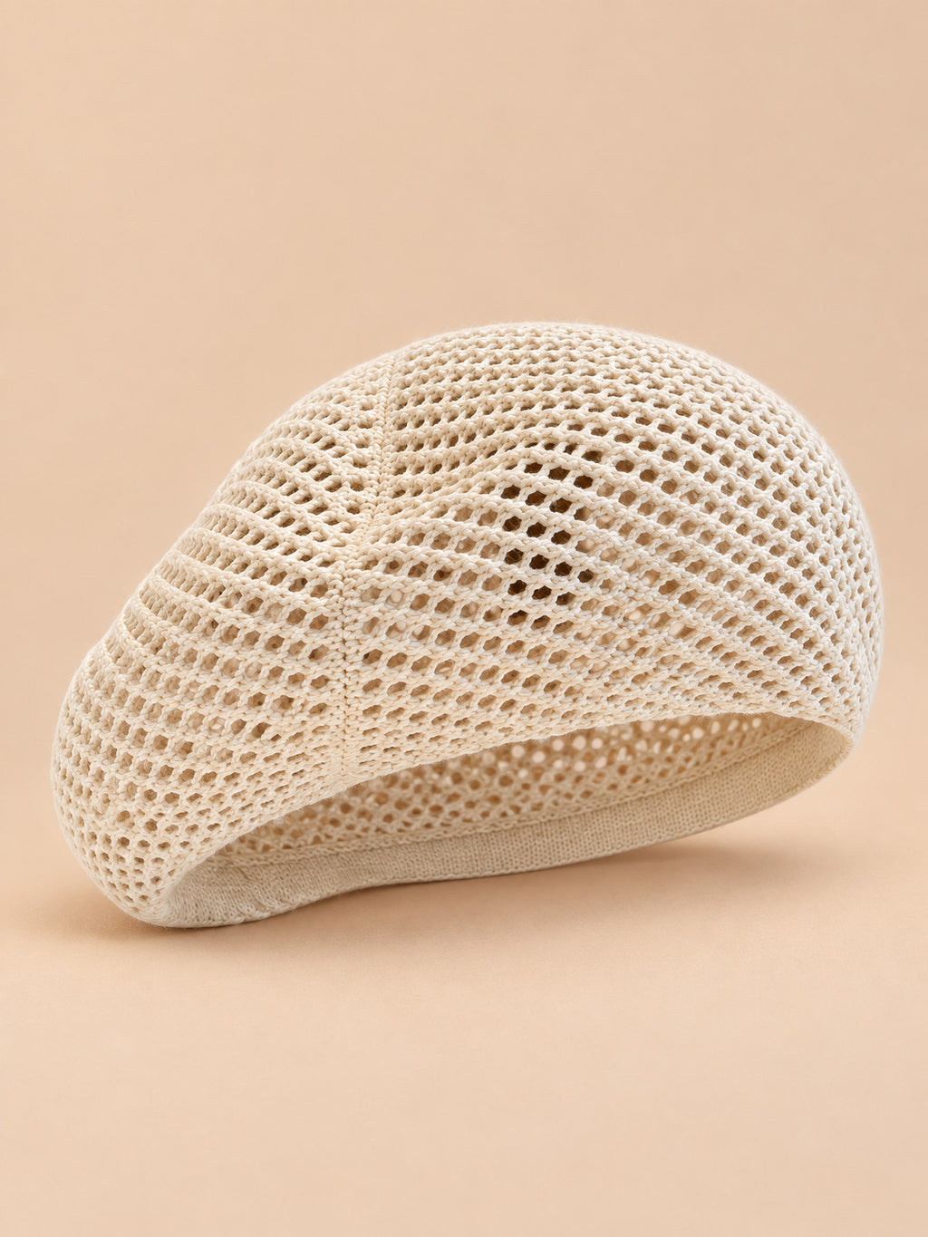 Béret d’artiste ajouré beige, vue de face sur fond pêche sable