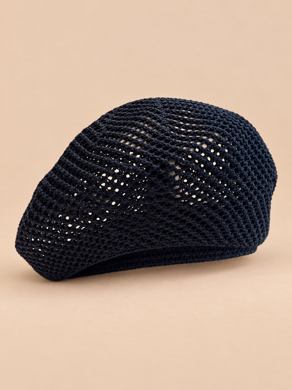 Béret d’artiste ajouré noir, vue de face sur fond pêche sable