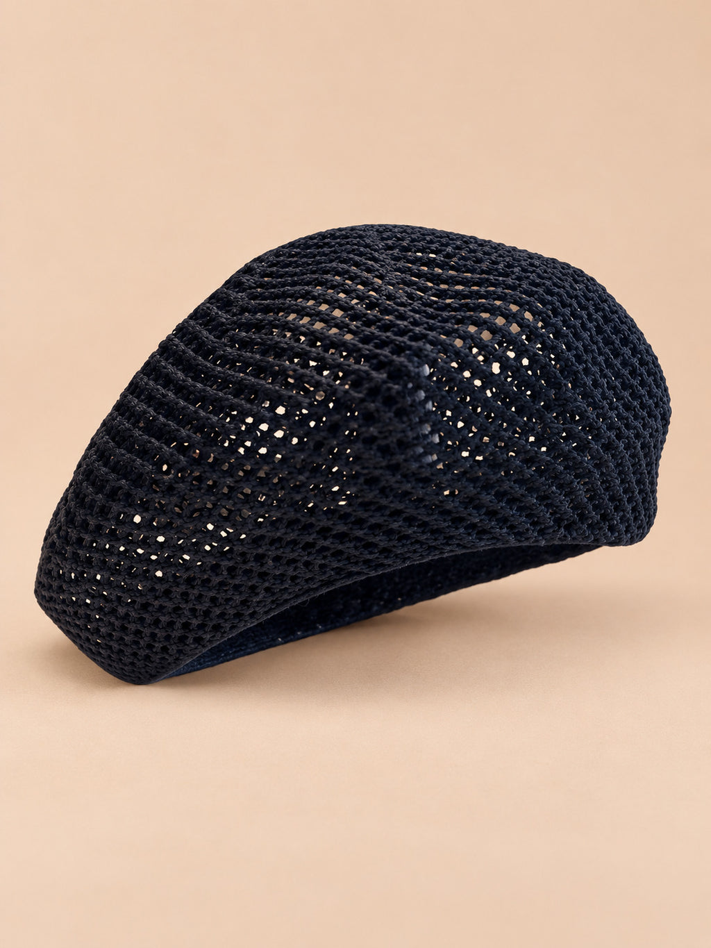Béret d’artiste ajouré noir, vue de trois quarts sur fond pêche sable