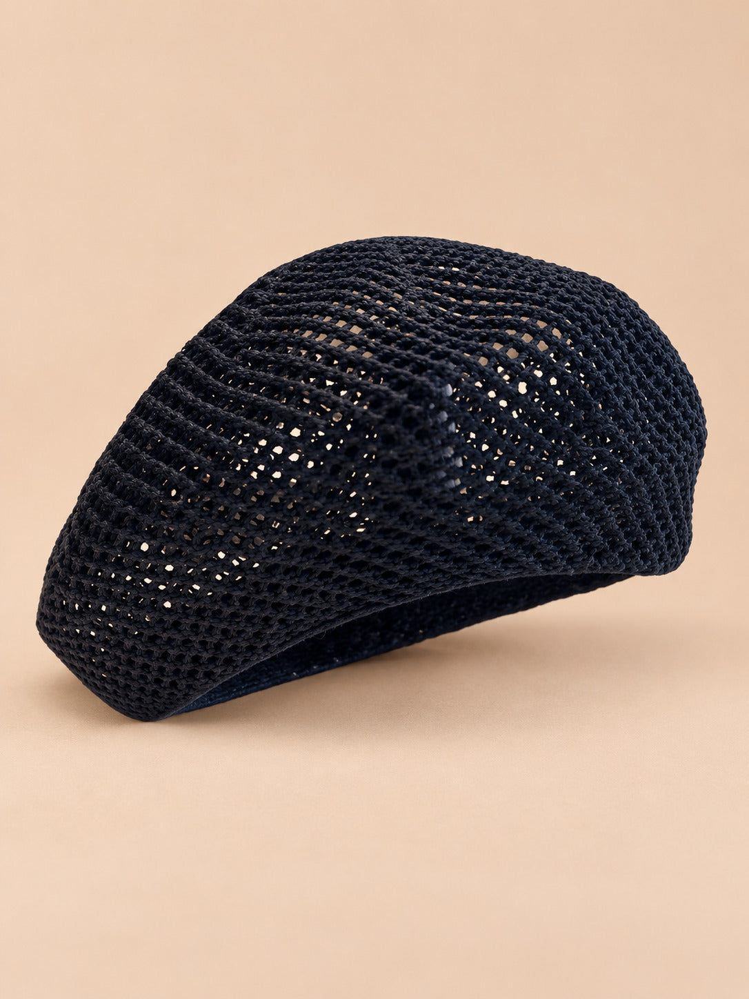 Béret d’artiste ajouré noir, vue de trois quarts sur fond pêche sable
