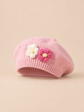 Béret bébé fille Rose à fleurs en relief au crochet, vue de face sur fond pêche sable