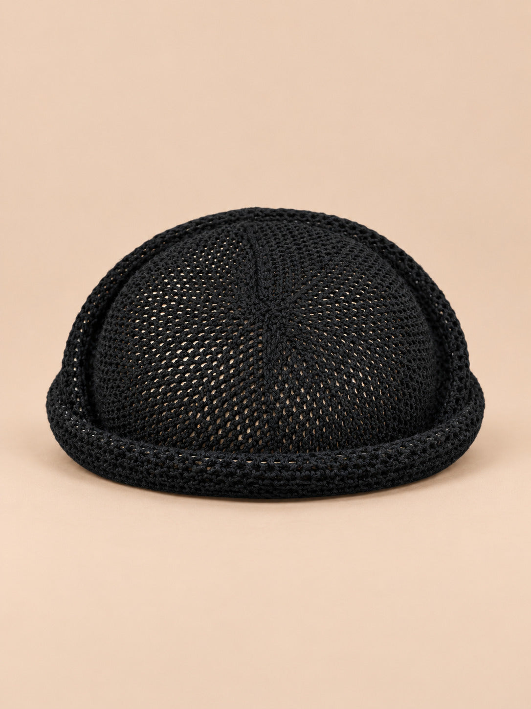 Béret bibi résille noir, vue de face sur fond pêche sable