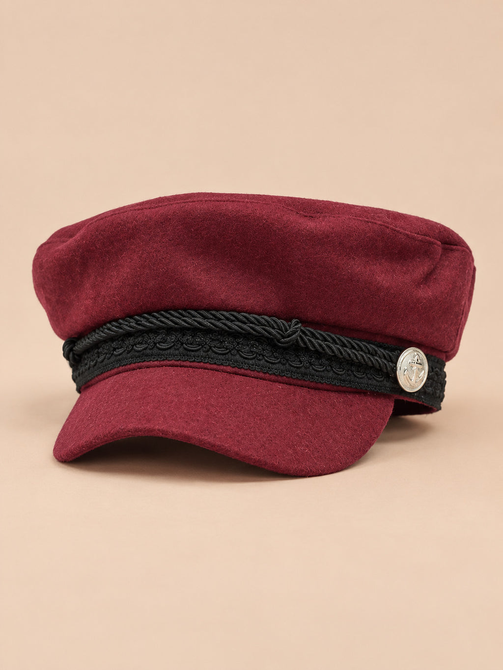 Gorra marinera de ocho paneles, estilo capitán, color burdeos, vista frontal, sobre fondo color arena y melocotón