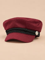 Gorra marinera de ocho paneles, estilo capitán, color burdeos, vista frontal, sobre fondo color arena y melocotón