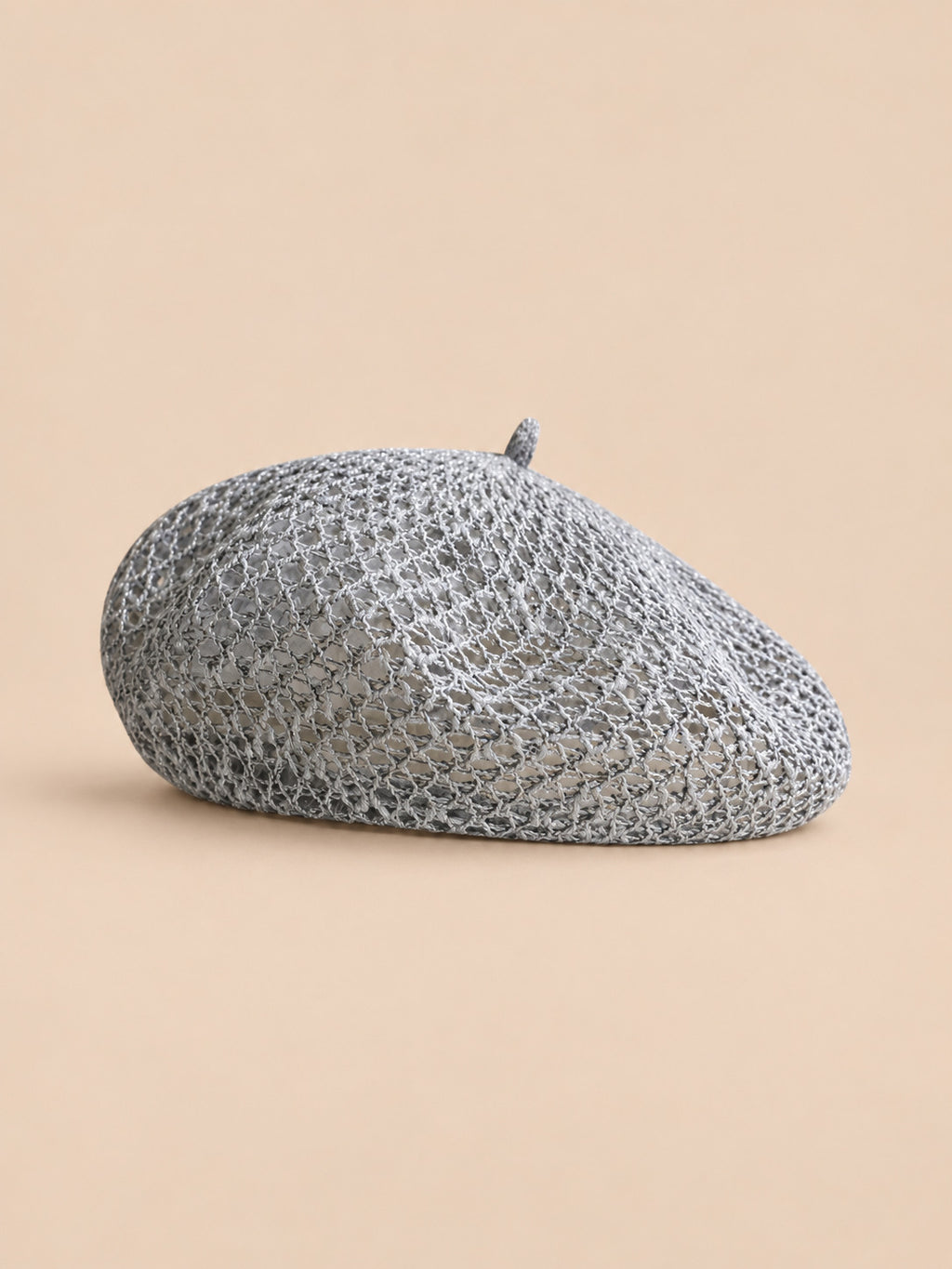 Béret citrouille ajouré gris, vue de face sur fond pêche sable