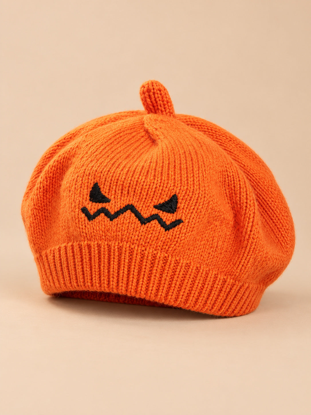 Béret enfant citrouille orange en maille avec visage brodé, vue de trois quarts