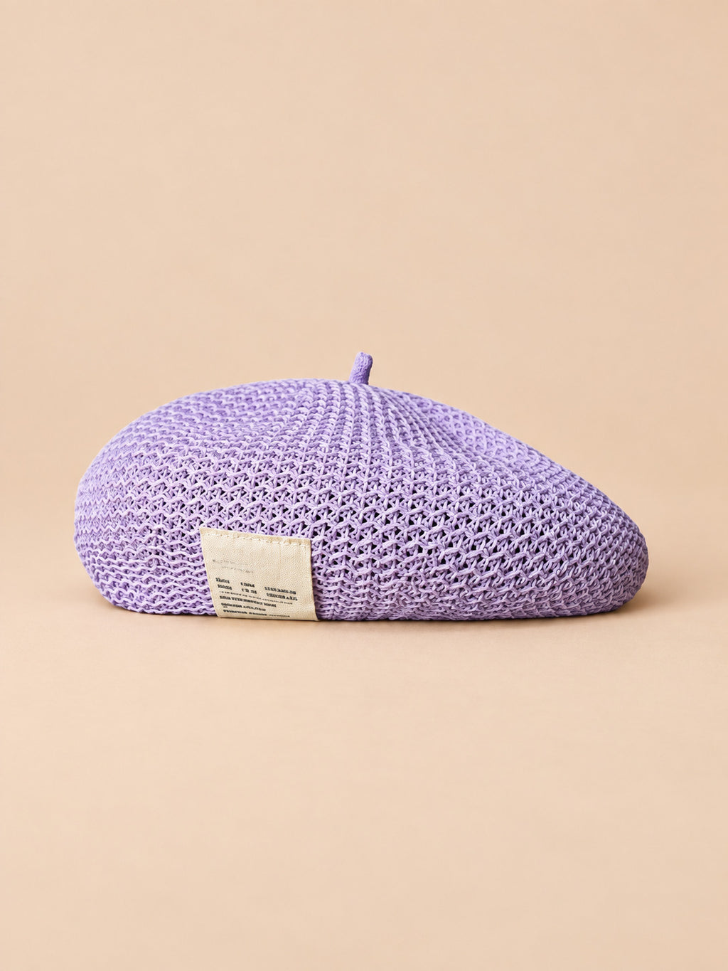 Béret d’été en lin ajouré lavande, vue de face sur fond pêche sable