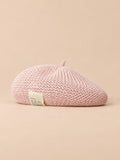 Béret d’été en lin ajouré rose, vue de face sur fond pêche sable