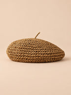 Béret d’été en paille de papier kaki, vue de face sur fond pêche sable