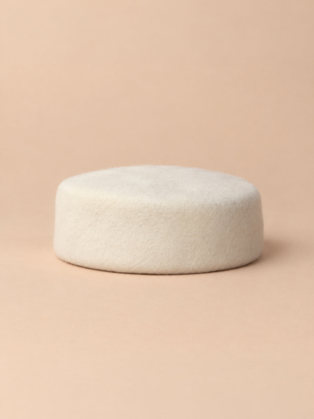 Béret femme en laine feutrée blanc cassé, forme plat, vue de face sur fond pêche sable
