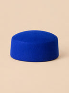 Béret femme en laine feutrée bleu, forme plat, vue de face sur fond pêche sable