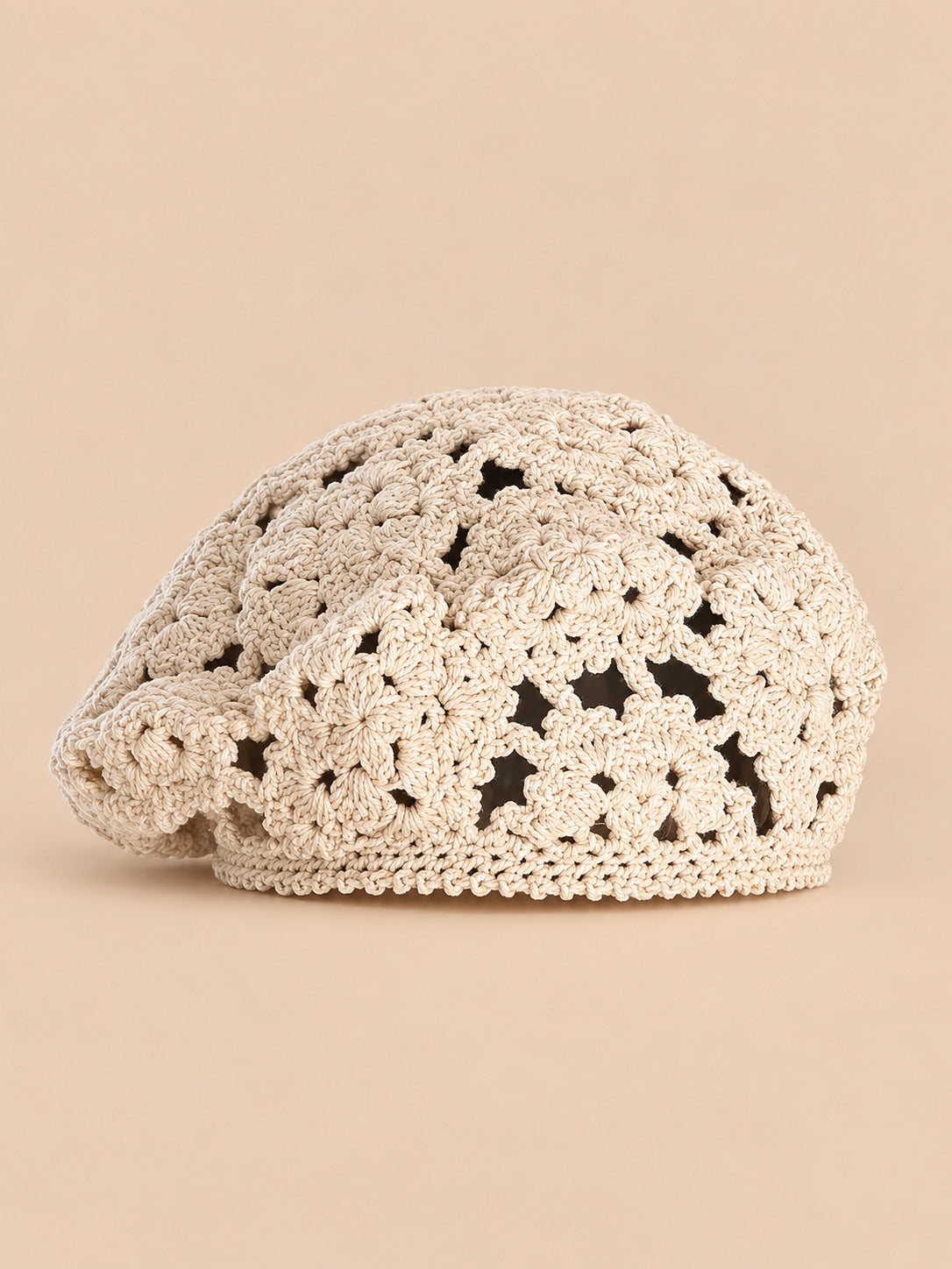 Béret femme beige à fleurs au crochet, vue de face sur fond pêche sable