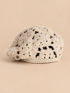 Béret femme beige à fleurs au crochet, vue de trois quarts sur fond pêche sable