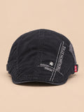 Gorra gavroche plana de algodón para todo el año, color negro, vista frontal, sobre fondo color arena y melocotón