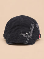 Gorra gavroche plana de algodón para todo el año, color negro, vista frontal, sobre fondo color arena y melocotón