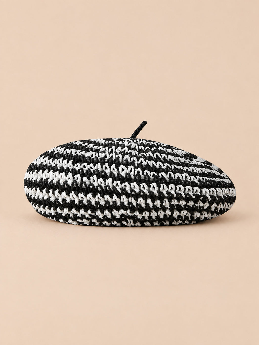 Béret plat effet paille Rayures noir et blanc, vue de face sur fond pêche sable