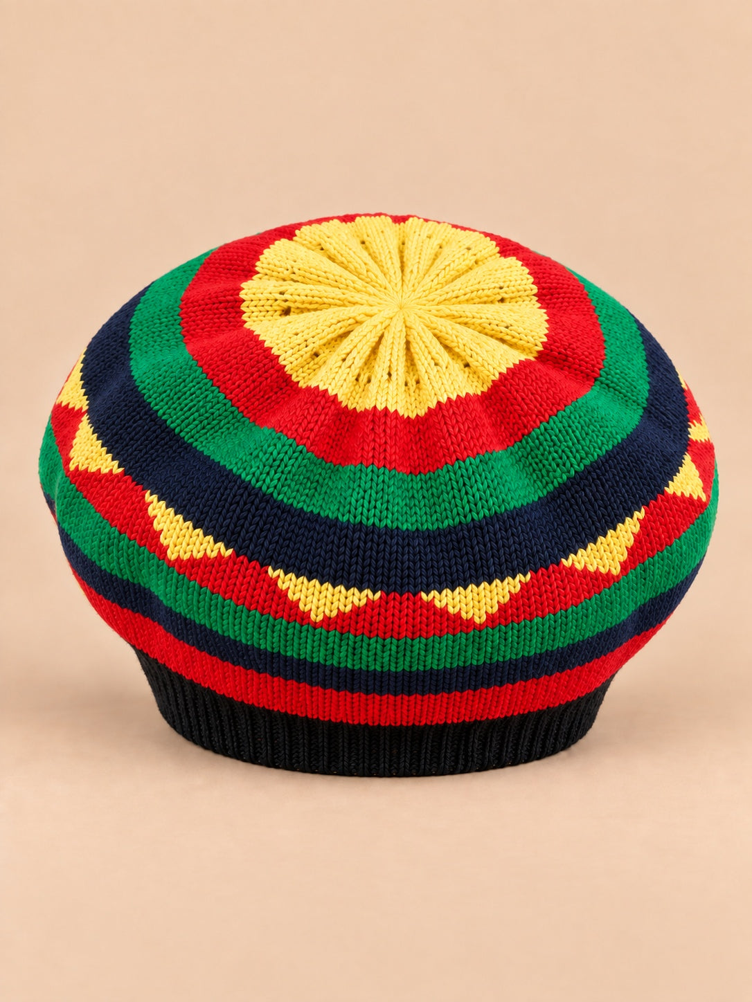 Béret rasta en maille multicolore 4, rayures et centre jaune, vue de face sur fond sable pêche.