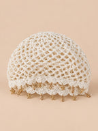 Béret rétro blanc ajouré au crochet à franges d'étoiles dorées, vue de face sur fond pêche sable