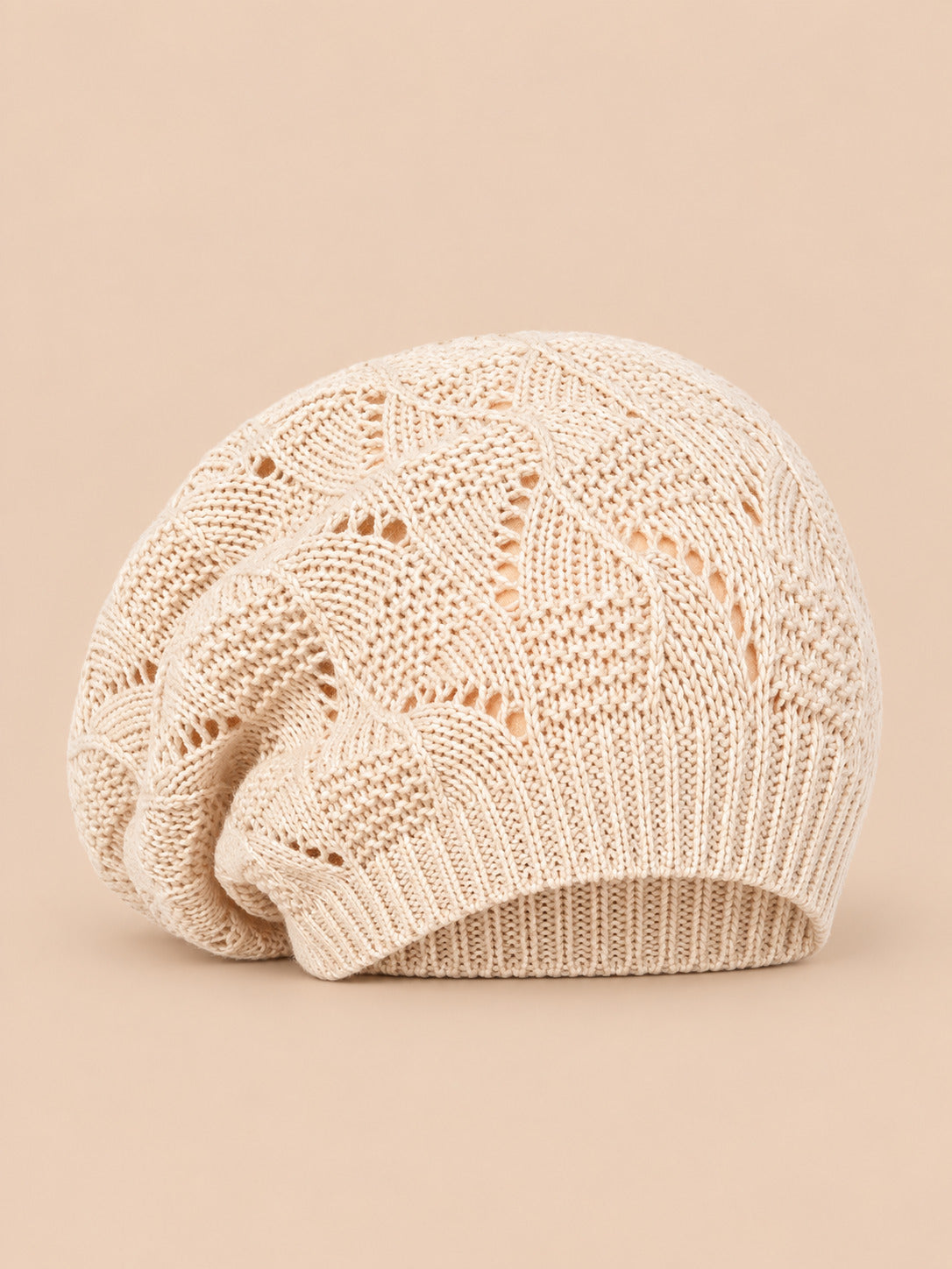 Bonnet béret torsadé ample beige, vue de face sur fond pêche sable