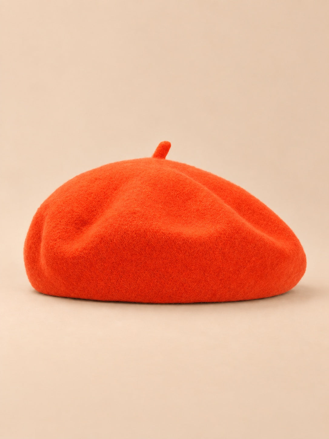 Béret uni femme en maille chaude orange, vue de face sur fond beige