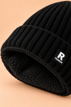 Detalle del gorro de mezcla de lana con forro polar negro y borde de canalé doblado formando una vuelta