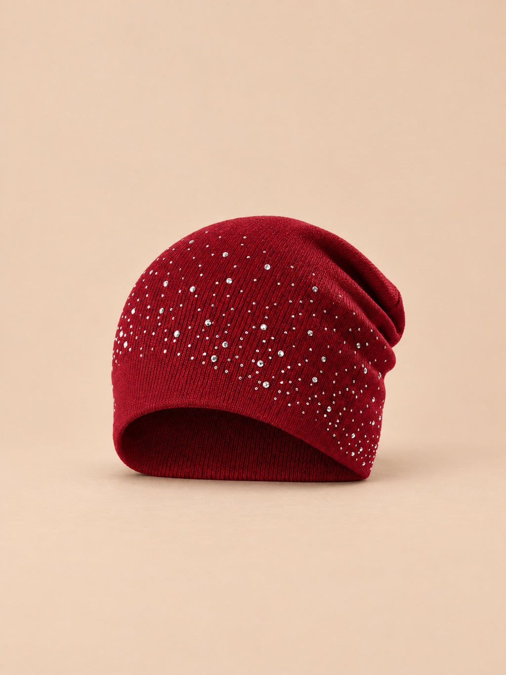 Gorro burdeos de mujer de punto con pedrería, de estilo streetwear, sobre fondo arena y melocotón