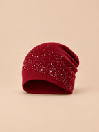 Gorro burdeos de mujer de punto con pedrería, de estilo streetwear, sobre fondo arena y melocotón