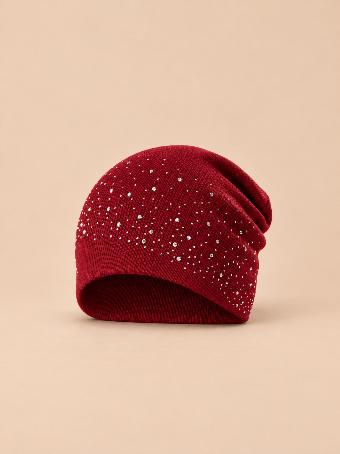 Gorro burdeos de mujer de punto con pedrería, de estilo streetwear, sobre fondo arena y melocotón