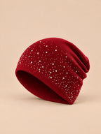 Gorro burdeos de mujer de punto con pedrería, fotografiado de tres cuartos sobre fondo arena y melocotón