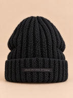 Bonnet noir en maille épaisse à revers et étiquette, vue de face.
