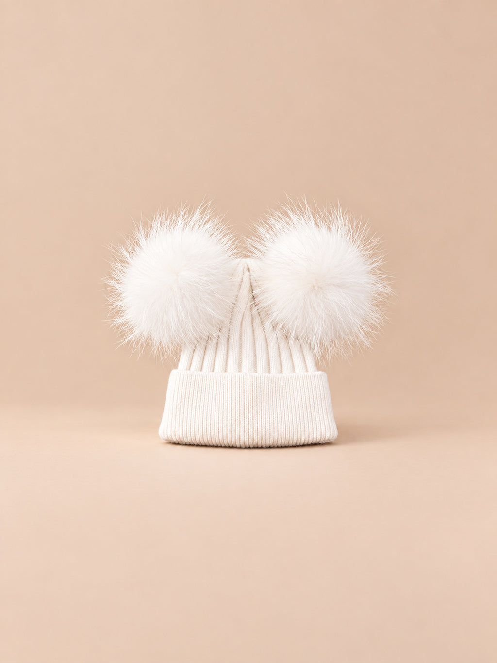 Bonnet double pompon, blanc, pompons assortis, vue de face sur fond pêche sable.