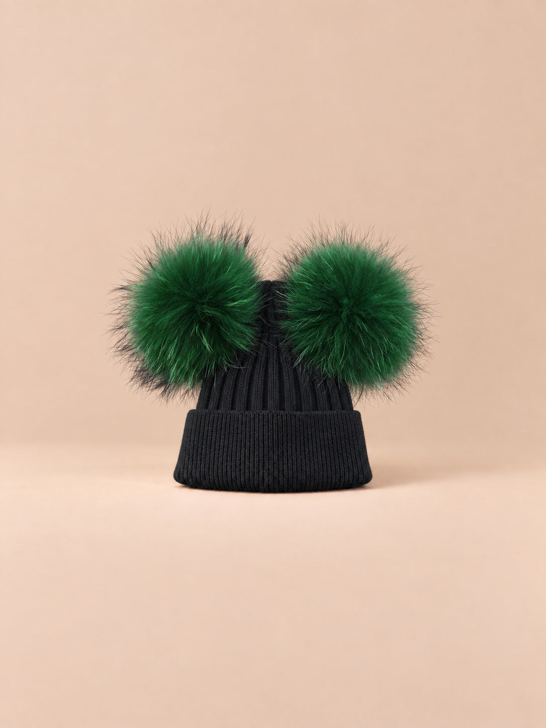 Bonnet double pompon, vert foncé, pompons assortis, vue de face sur fond pêche sable.