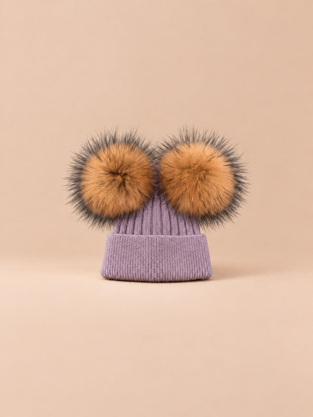 Bonnet double pompon, violet, pompons naturels, vue de face sur fond pêche sable.