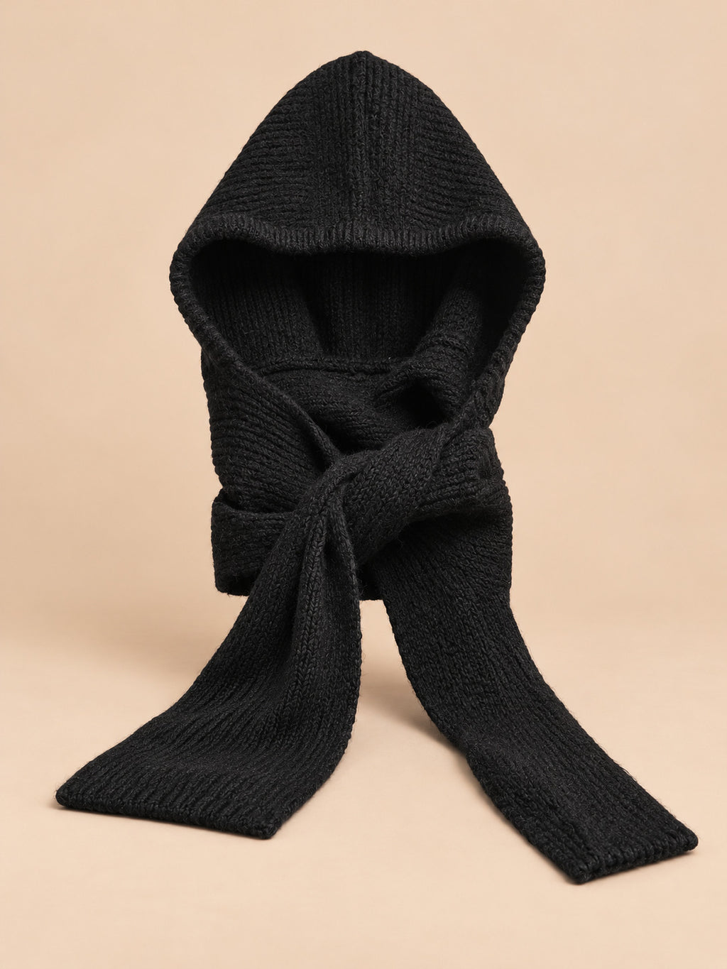 Cagoule bonnet-écharpe noir en maille, vue de face sur fond pêche sable