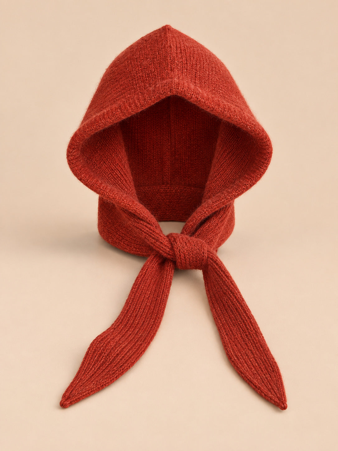 Cagoule bonnet-écharpe rouge a en maille, vue de face sur fond pêche sable