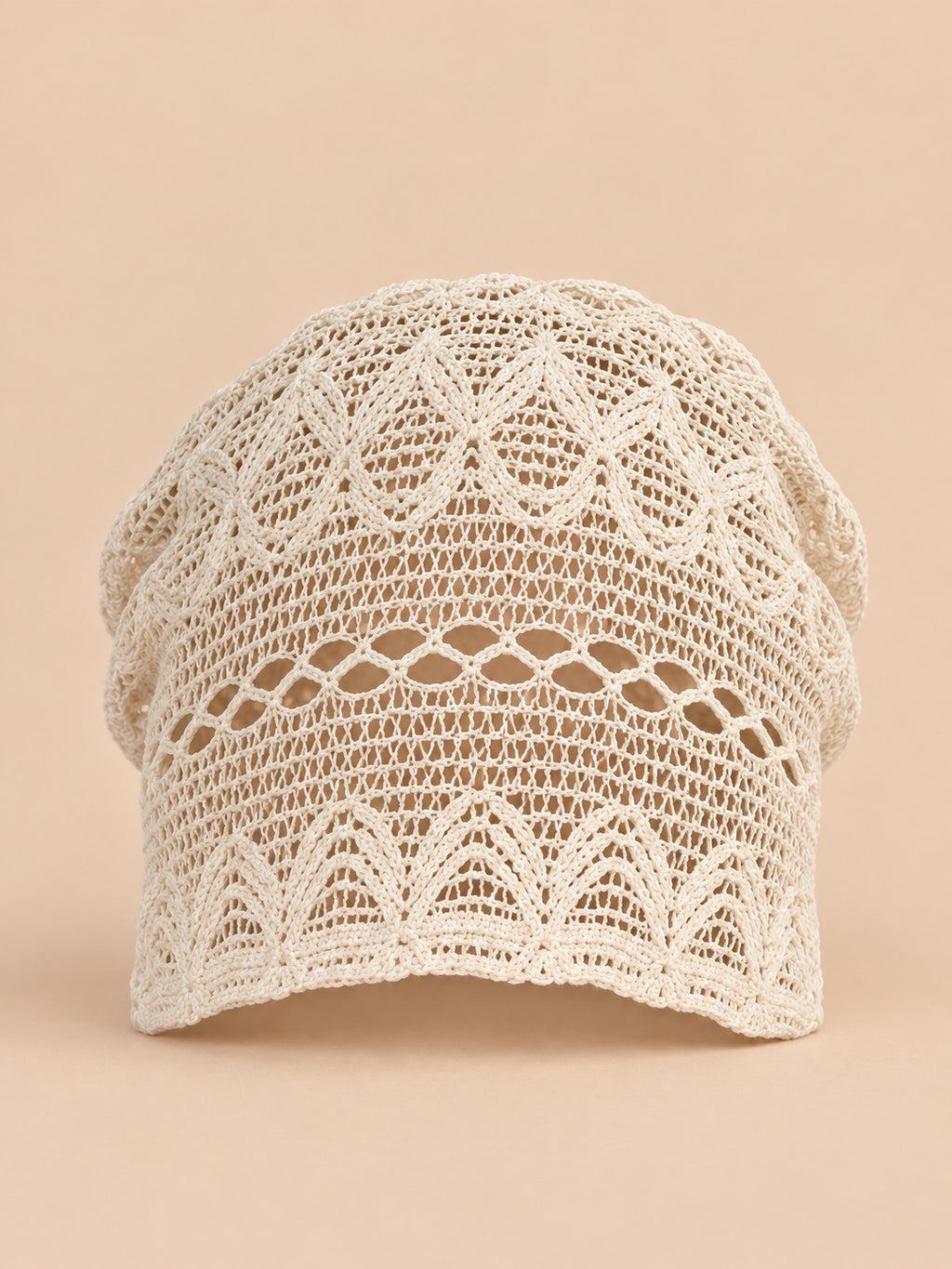 Bonnet calotte froncée beige en dentelle crochet ajourée, vue de face sur fond pêche sable