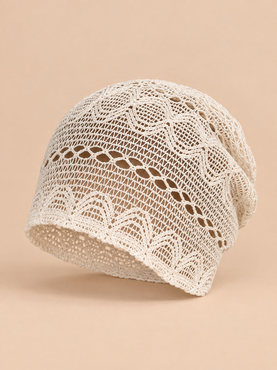 Bonnet calotte froncée beige en dentelle crochet ajourée, vue trois quarts sur fond pêche sable