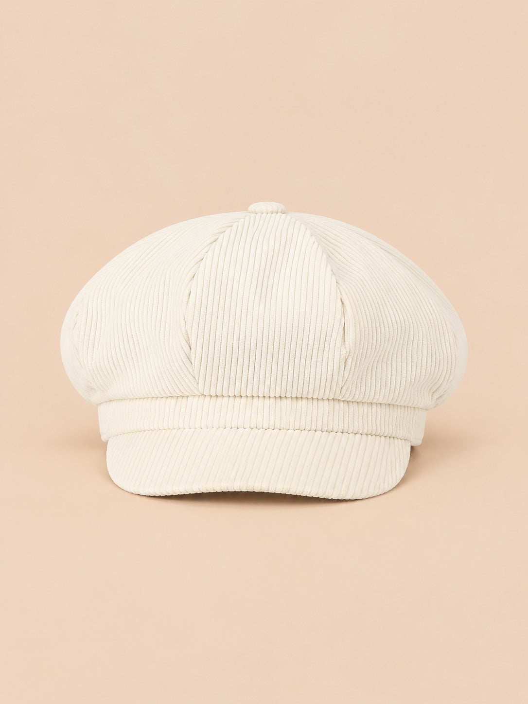 Casquette gavroche octogonale en velours côtelé beige, vue de face sur fond pêche sable