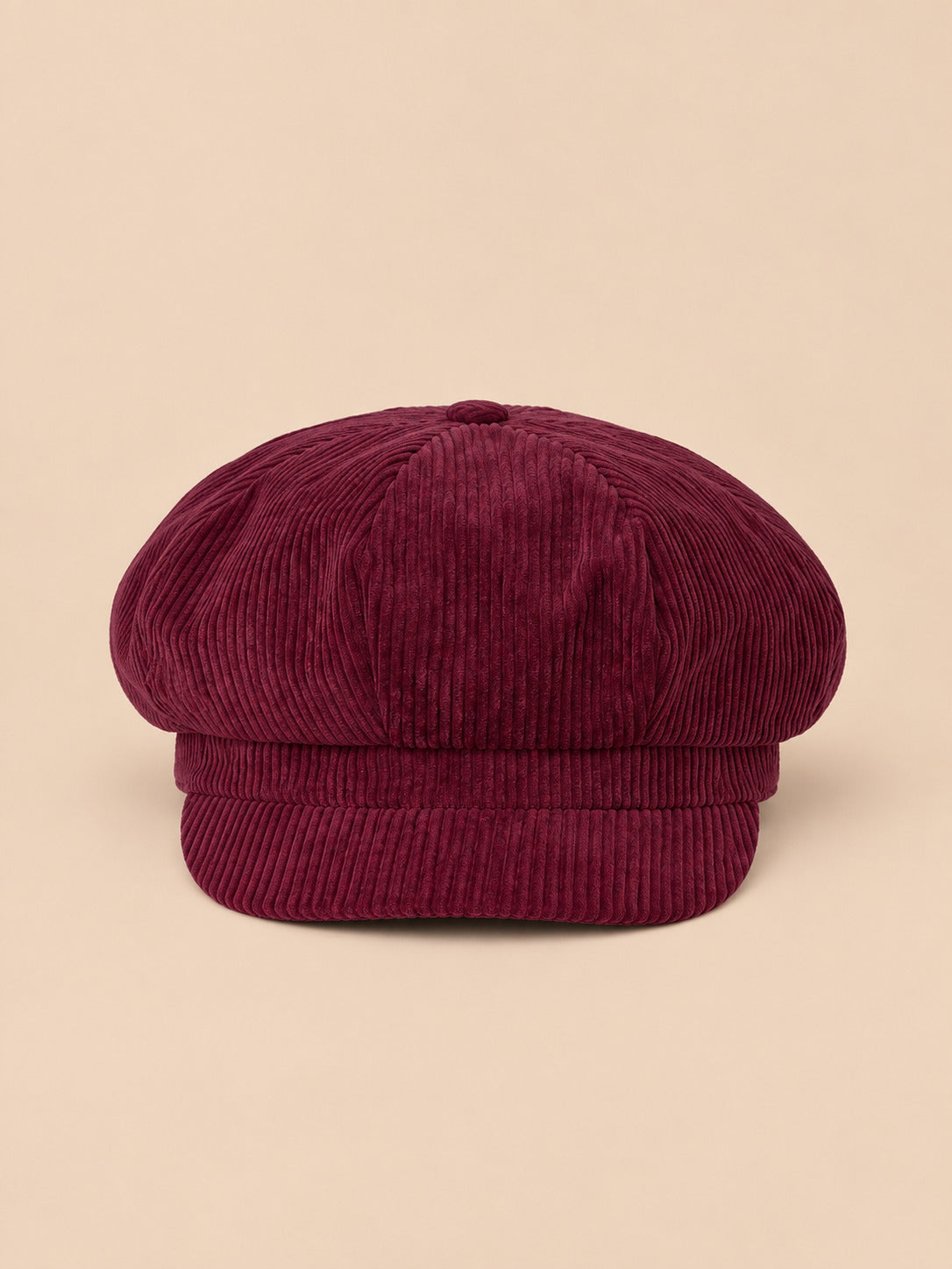 Casquette gavroche octogonale en velours côtelé bordeaux, vue de face sur fond pêche sable