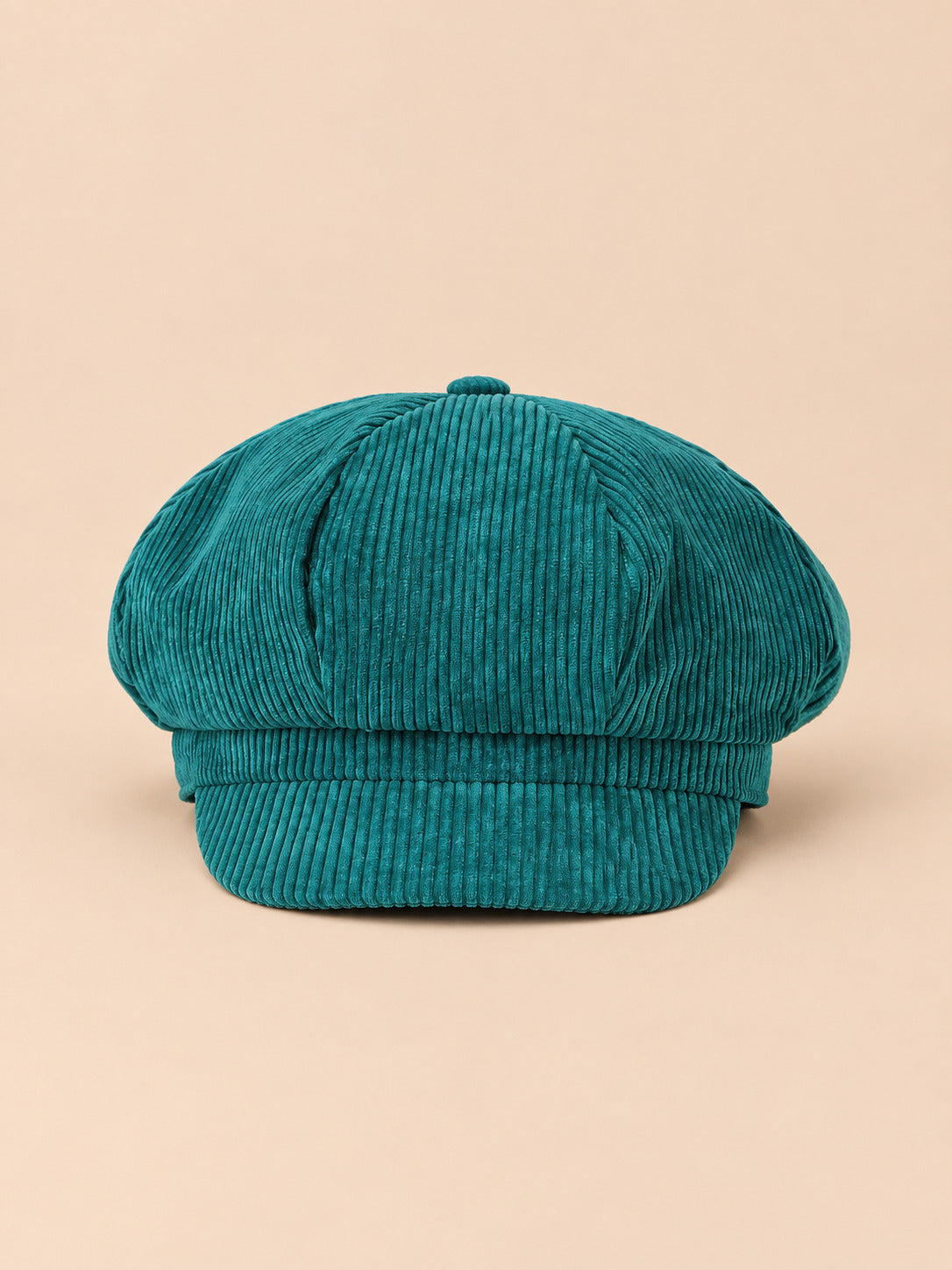 Casquette gavroche octogonale en velours côtelé vert, vue de face sur fond pêche sable