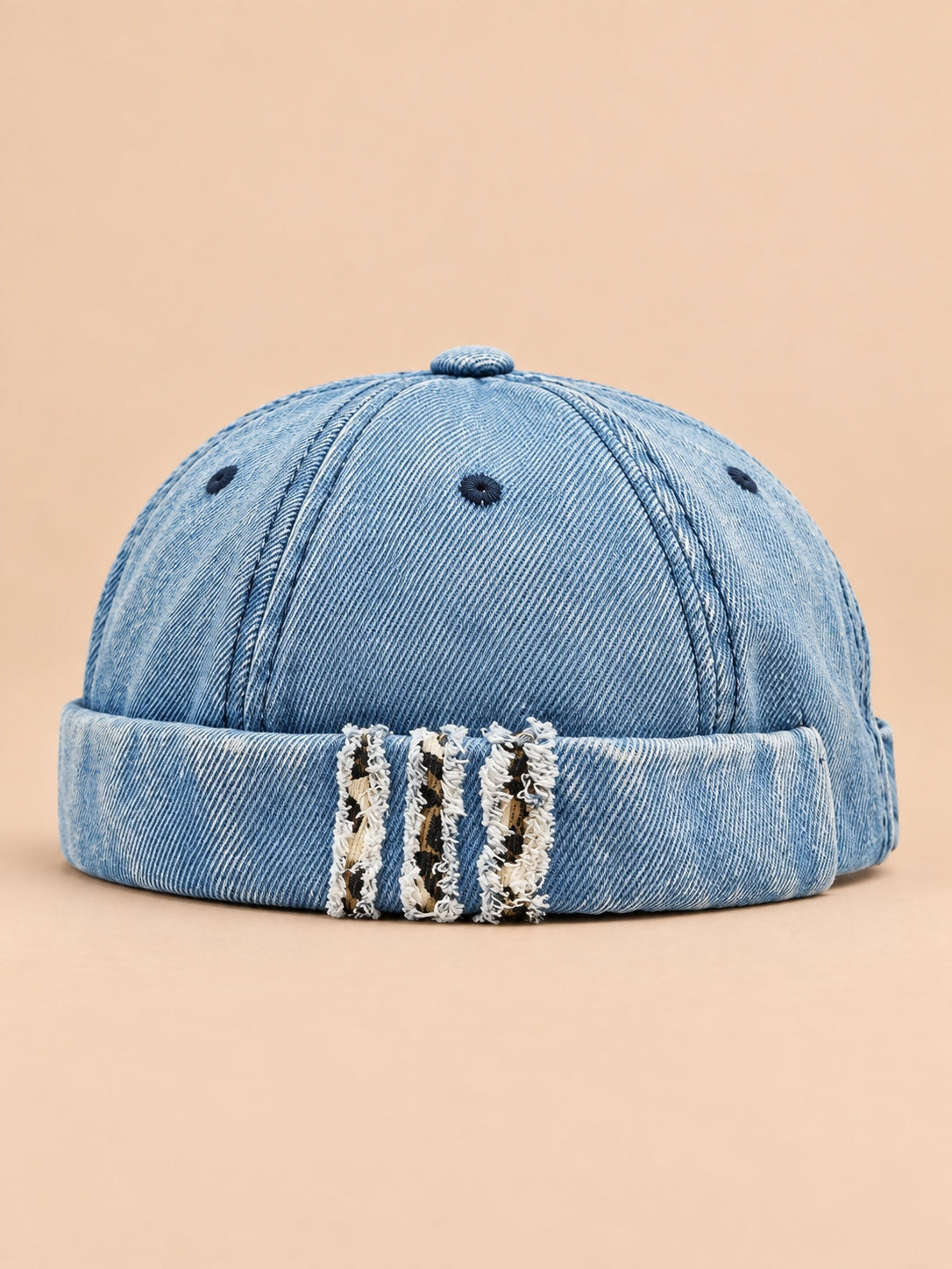 Bonnet docker en denim bleu, revers effiloché à détails léopard, vue de face.