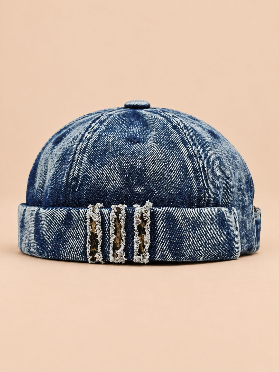 Bonnet docker en denim bleu marine, revers effiloché à détails léopard, vue de face.