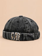 Bonnet docker en denim noir, revers effiloché à détails léopard, vue de trois quarts.
